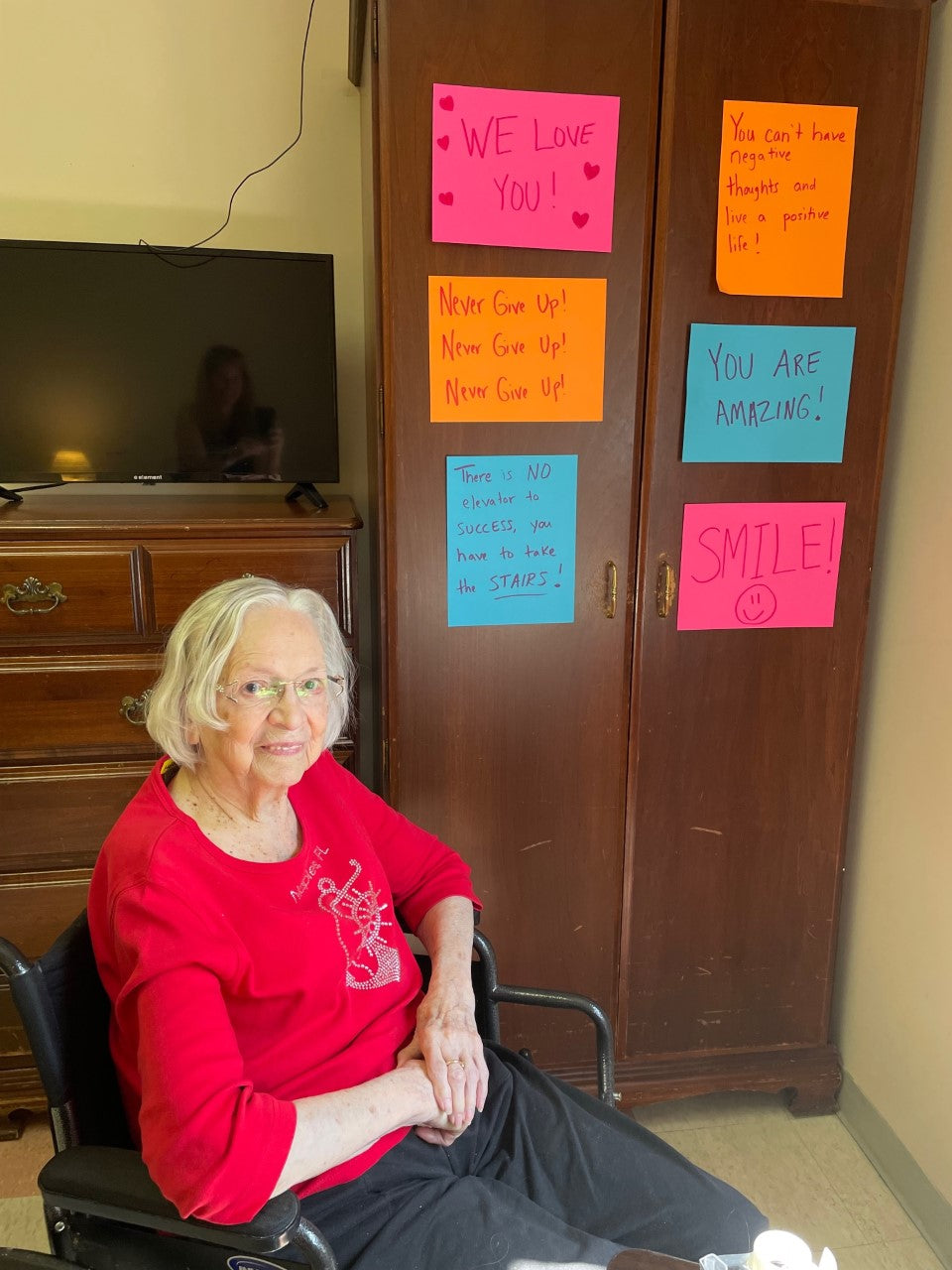 Grandma sitting in front of her handmade signs on bright paper colors.